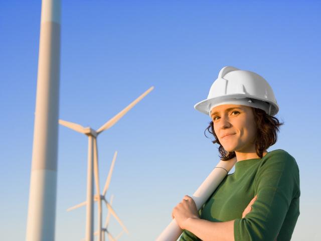 Woman in hard hat at wind turbines